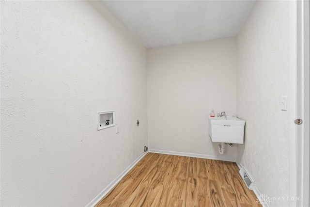 washroom featuring washer hookup, sink, and light hardwood / wood-style floors