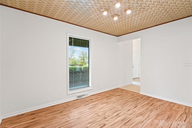 empty room featuring ornamental molding and light wood-type flooring