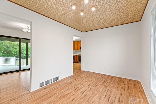 unfurnished room featuring ornamental molding and light wood-type flooring