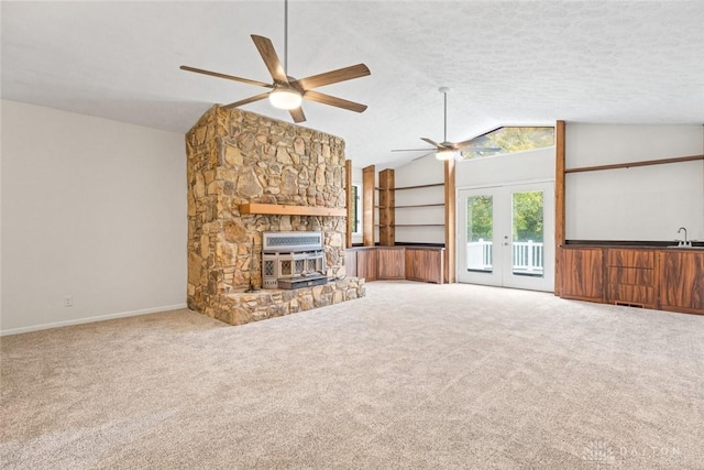 unfurnished living room with sink, carpet flooring, a fireplace, vaulted ceiling, and french doors