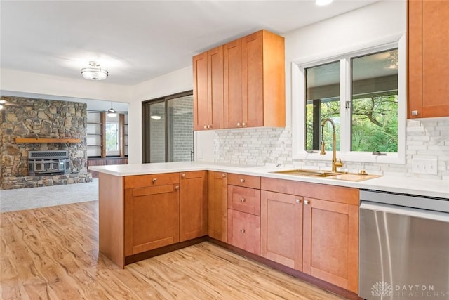 kitchen with sink, decorative backsplash, stainless steel dishwasher, kitchen peninsula, and light hardwood / wood-style flooring