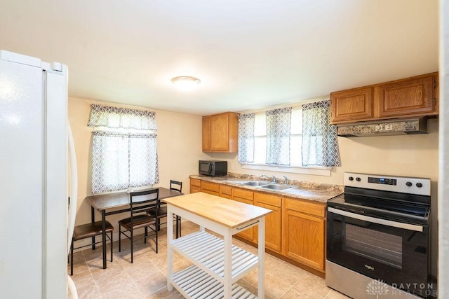 kitchen featuring sink, white refrigerator, premium range hood, and stainless steel range with electric cooktop