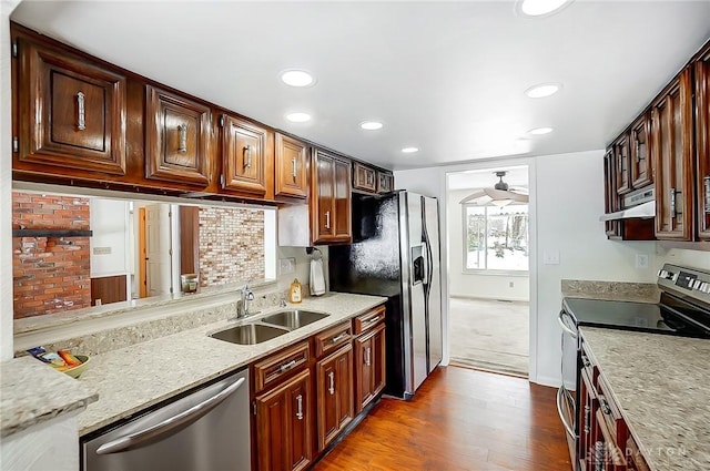 kitchen with sink, hardwood / wood-style flooring, light stone counters, ceiling fan, and stainless steel appliances