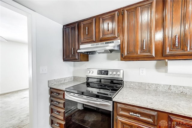 kitchen featuring stainless steel electric stove, light stone countertops, and light colored carpet