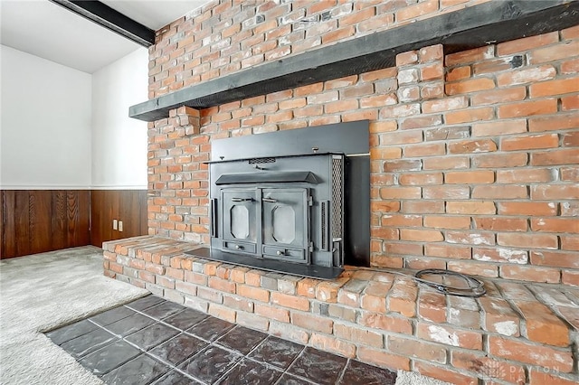 room details featuring carpet, a wood stove, beam ceiling, and wood walls