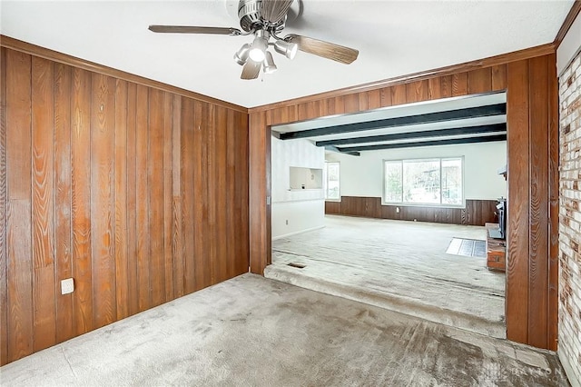 carpeted spare room featuring ceiling fan and wood walls