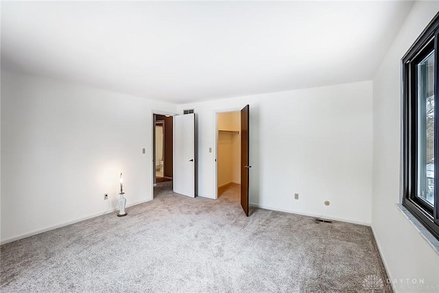 unfurnished bedroom with light carpet and a spacious closet