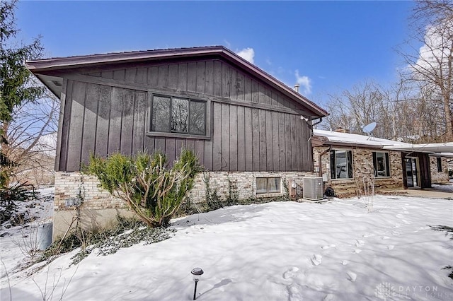 snow covered property with central air condition unit