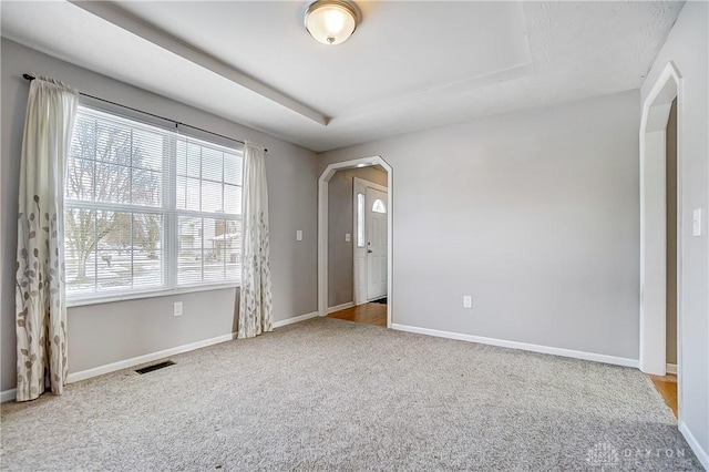 carpeted empty room featuring a tray ceiling