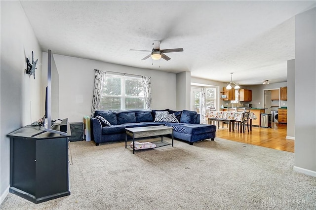 carpeted living room featuring ceiling fan, plenty of natural light, and a textured ceiling