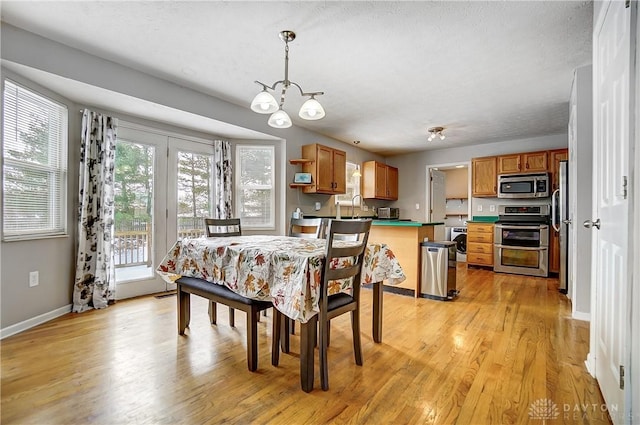 dining space with sink, light hardwood / wood-style flooring, a textured ceiling, washer / dryer, and a chandelier