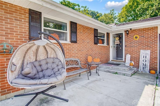 entrance to property with brick siding and a patio