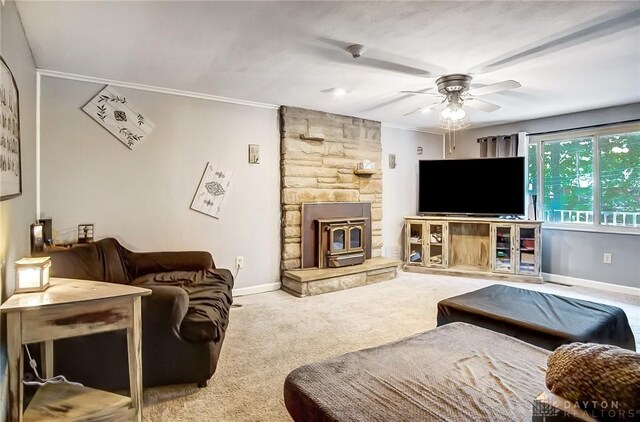 living room with crown molding, carpet, a wood stove, and ceiling fan