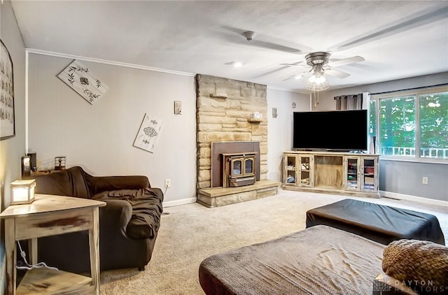 living area with baseboards, a ceiling fan, ornamental molding, a wood stove, and carpet