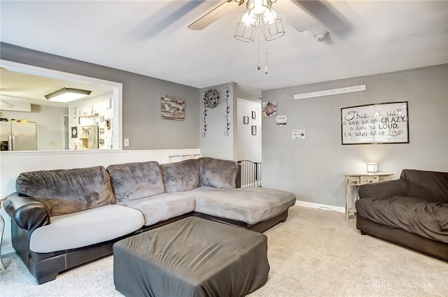 living area featuring light carpet, ceiling fan, and baseboards