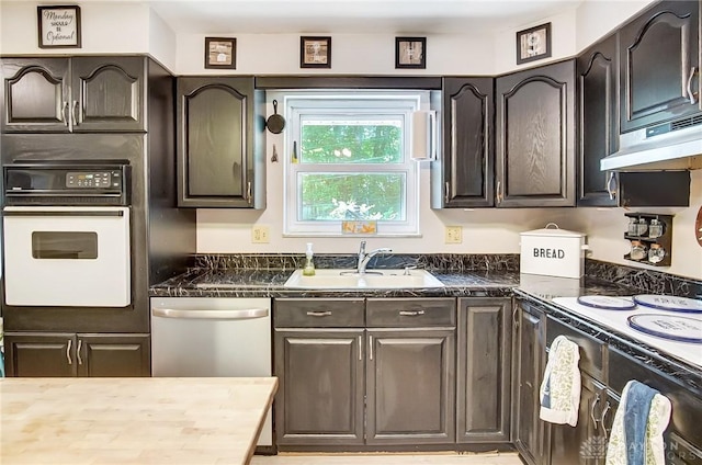 kitchen with oven, under cabinet range hood, a sink, dishwasher, and dark countertops