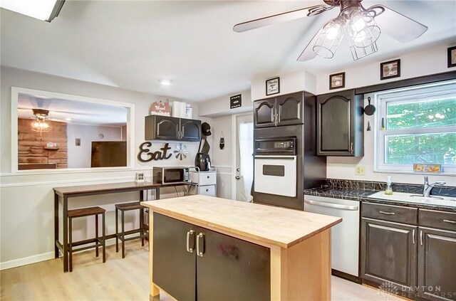 kitchen with sink, dark brown cabinets, appliances with stainless steel finishes, ceiling fan, and light hardwood / wood-style floors