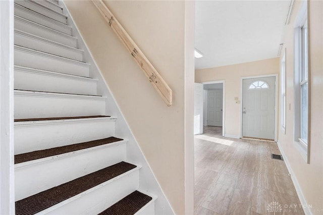 foyer entrance featuring visible vents, stairway, and baseboards