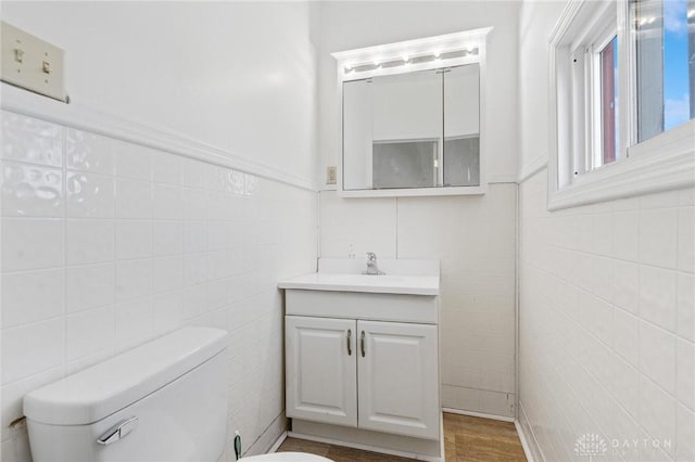 bathroom featuring vanity, tile walls, and toilet