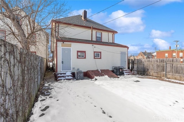 snow covered rear of property with central air condition unit