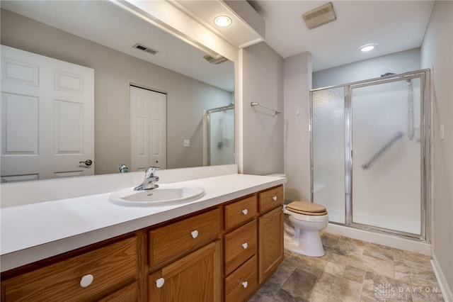 bathroom featuring vanity, a shower with shower door, and toilet