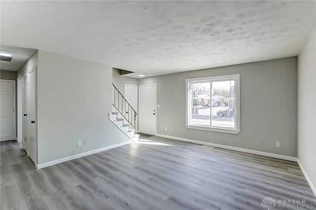 unfurnished room with a textured ceiling and light wood-type flooring