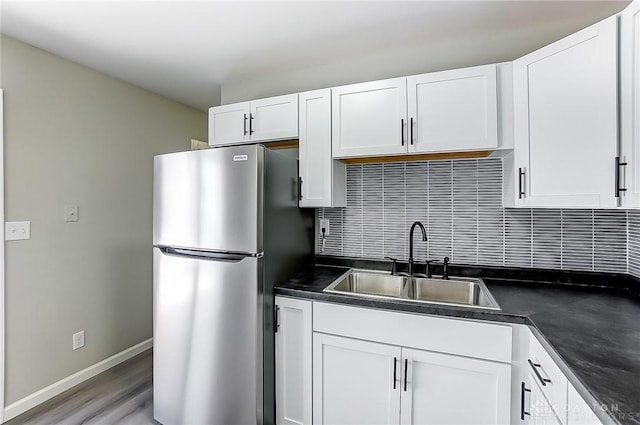 kitchen featuring stainless steel refrigerator, white cabinetry, sink, backsplash, and light hardwood / wood-style flooring