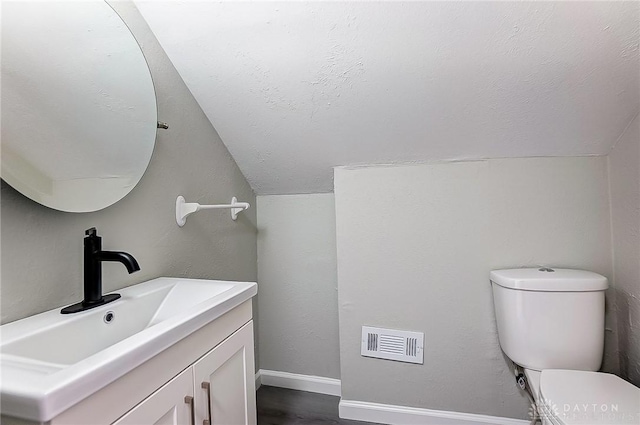 bathroom featuring lofted ceiling, vanity, toilet, and a textured ceiling