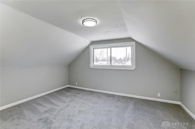 additional living space featuring lofted ceiling, carpet floors, and a textured ceiling