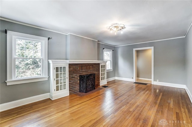 unfurnished living room featuring crown molding, a fireplace, baseboards, and wood finished floors