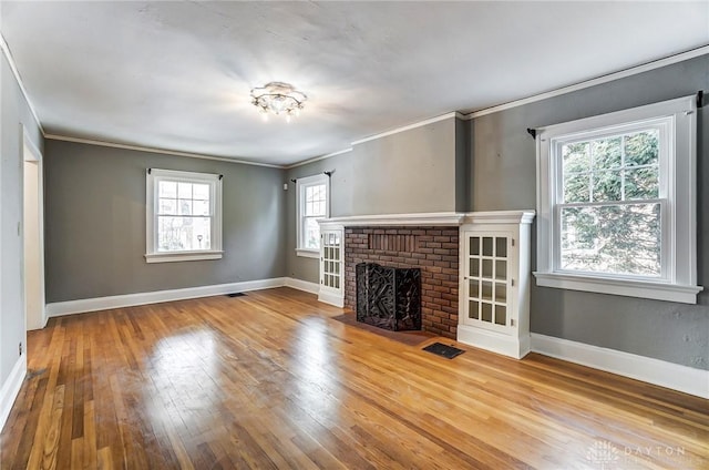 unfurnished living room with a fireplace, wood finished floors, visible vents, and baseboards