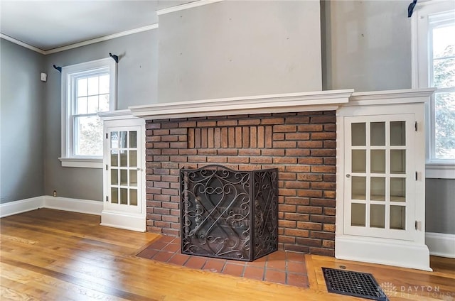 interior details featuring ornamental molding, a fireplace, wood finished floors, and baseboards