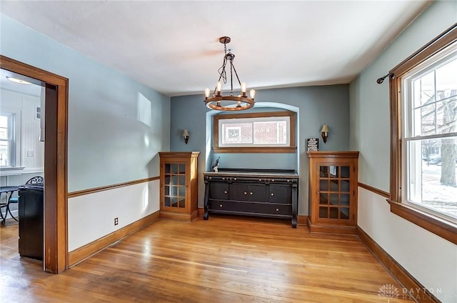 dining area with a chandelier, baseboards, and light wood-style floors