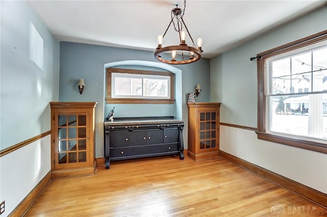 interior space featuring light wood-style floors, a chandelier, and baseboards