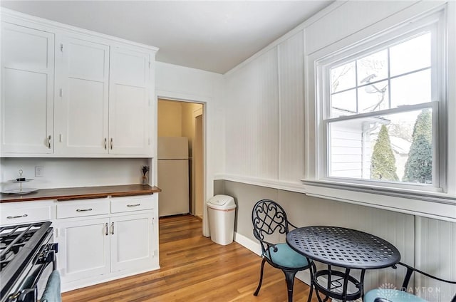 kitchen featuring range with gas stovetop, freestanding refrigerator, white cabinets, and wooden counters