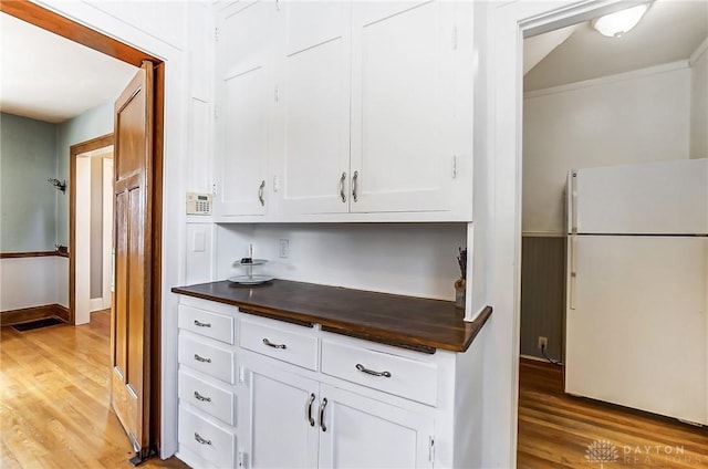 kitchen featuring dark countertops, wood finished floors, freestanding refrigerator, and white cabinets