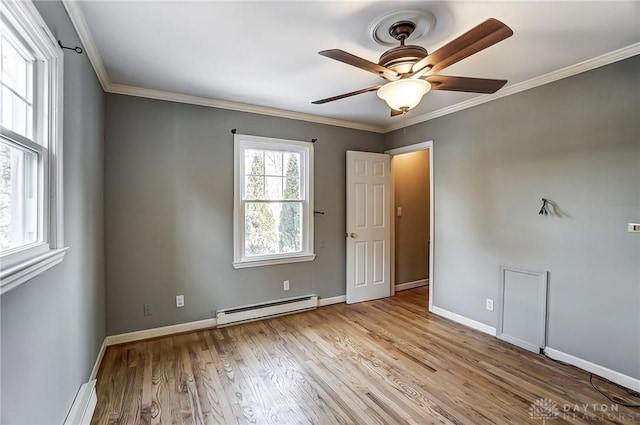 unfurnished room with a baseboard heating unit, ornamental molding, light wood-style flooring, and baseboards