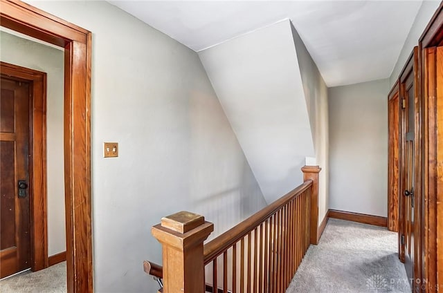 hall featuring baseboards, light carpet, and an upstairs landing