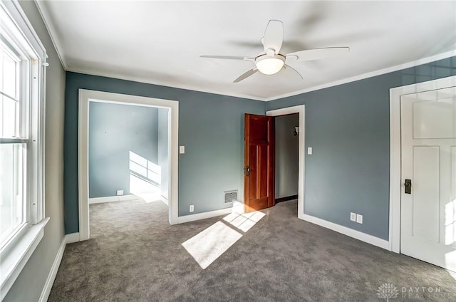 empty room with visible vents, dark carpet, ornamental molding, ceiling fan, and baseboards