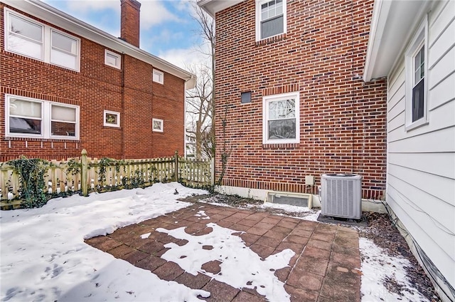 snow covered patio with cooling unit and fence