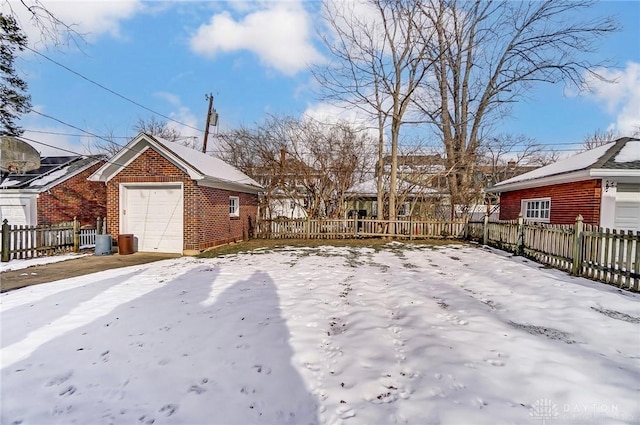 yard covered in snow featuring an outbuilding, fence, and a detached garage