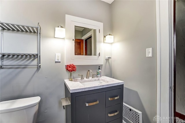 bathroom with toilet, vanity, and visible vents