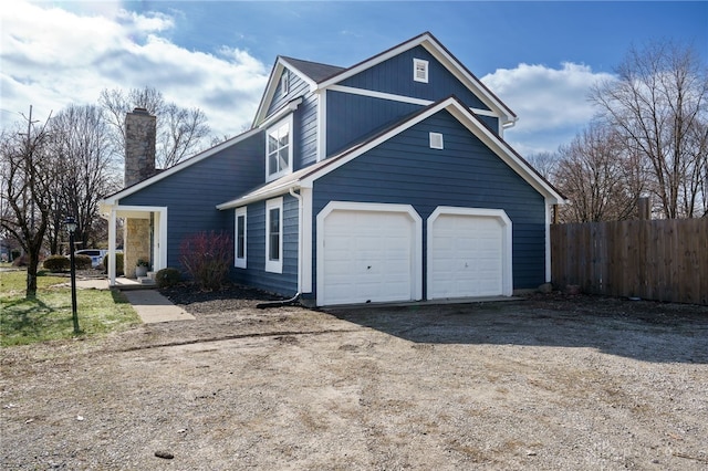 traditional-style home featuring a garage, fence, and dirt driveway