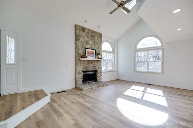 unfurnished living room with baseboards, ceiling fan, light wood-type flooring, a fireplace, and high vaulted ceiling