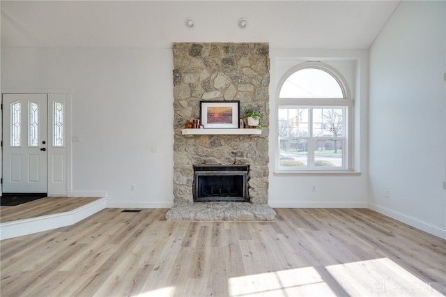 unfurnished living room featuring visible vents, a fireplace, baseboards, and wood finished floors