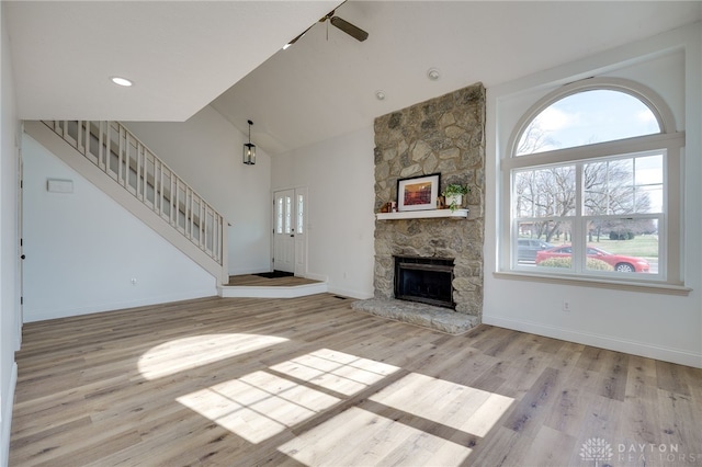 unfurnished living room with light wood-type flooring, stairs, baseboards, and a fireplace