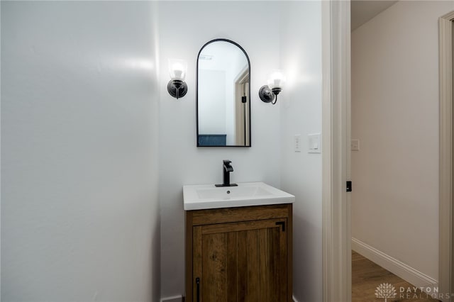 bathroom with wood finished floors, vanity, and baseboards