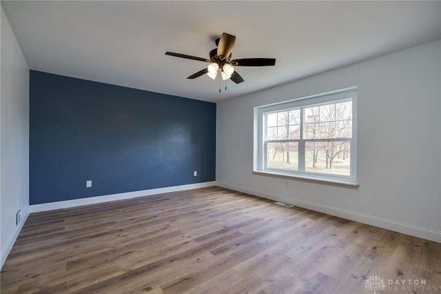 empty room featuring baseboards, visible vents, and wood finished floors