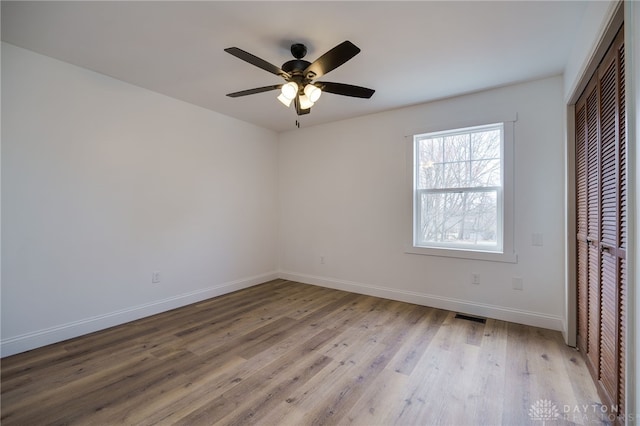 unfurnished bedroom featuring visible vents, baseboards, ceiling fan, light wood-style floors, and a closet