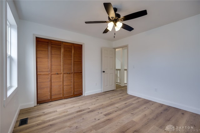 unfurnished bedroom with a closet, visible vents, baseboards, and wood finished floors